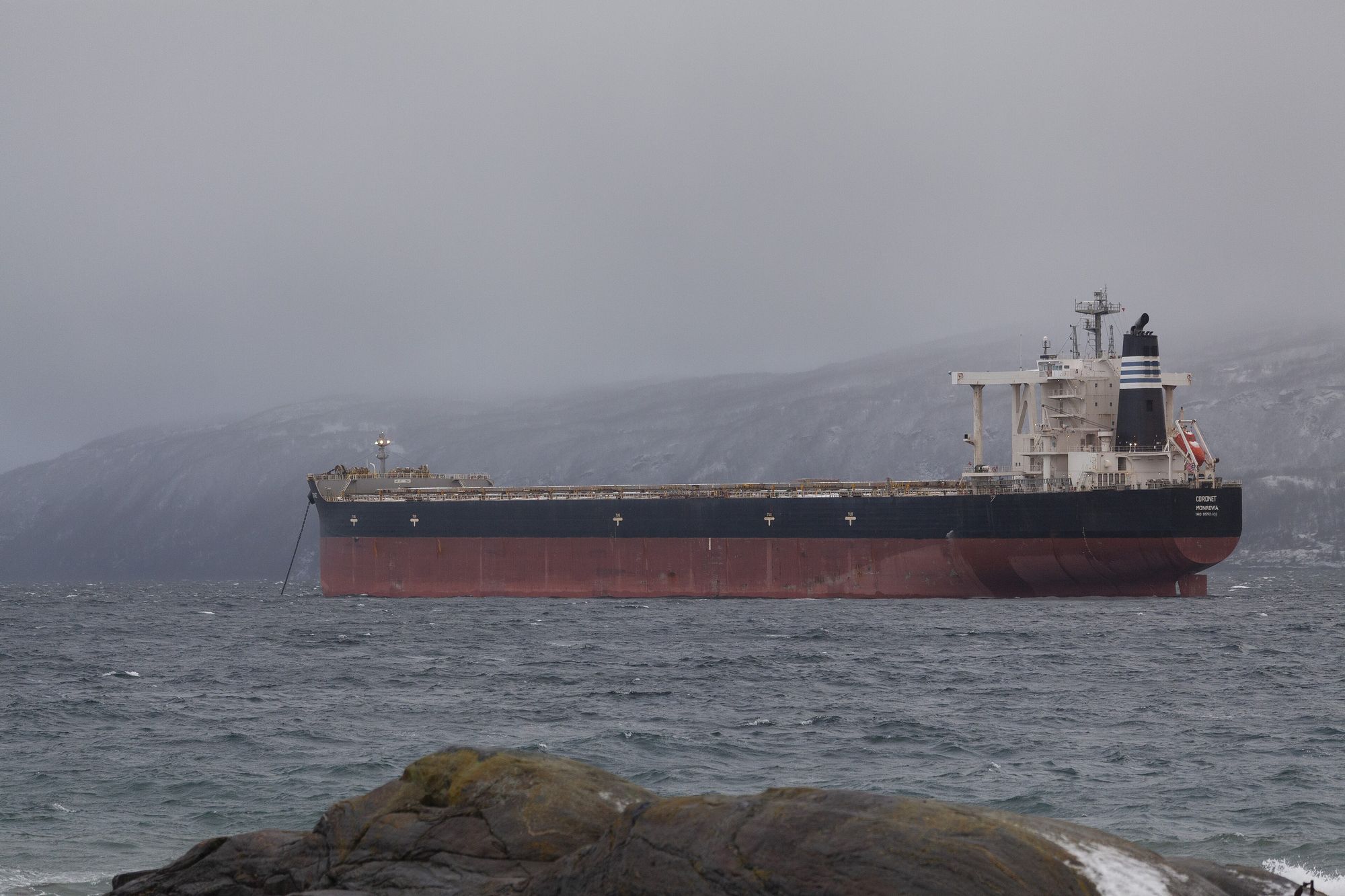 A bulk carrier at anchor in a grey northern fjord