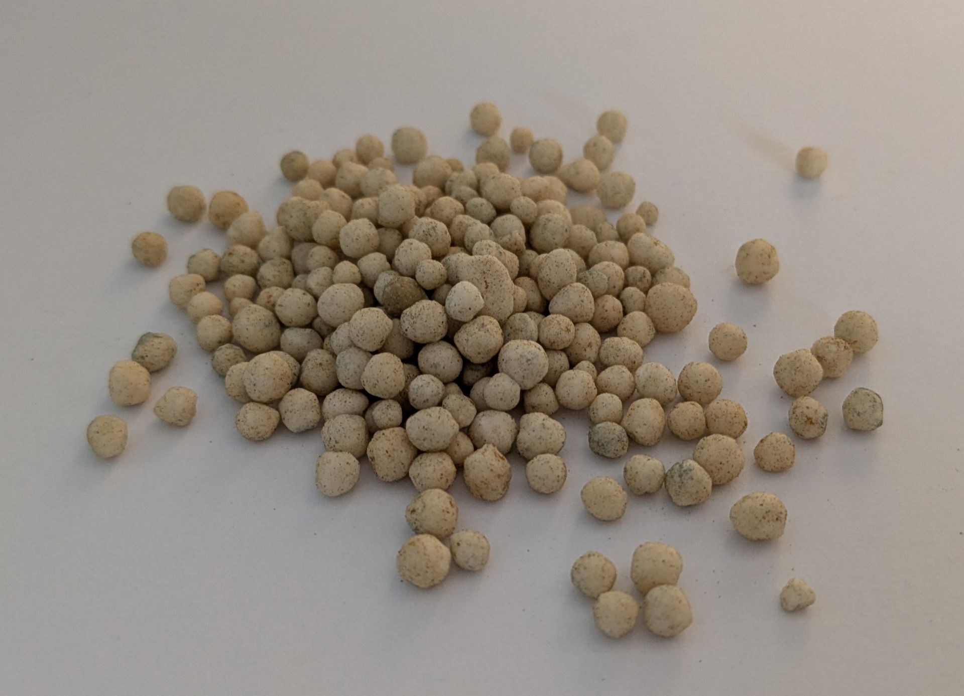 Pale fertilizer pellets of calcium ammonium nitrate, close up
