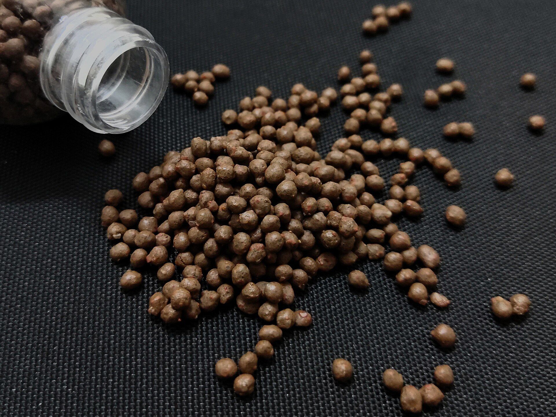 Brown compound fertilizer granules spilled on dark cloth